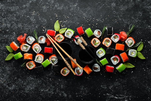 Grande conjunto de pedaços de rolos de sushi no fundo de pedra preta Vista superior Espaço livre para o seu texto