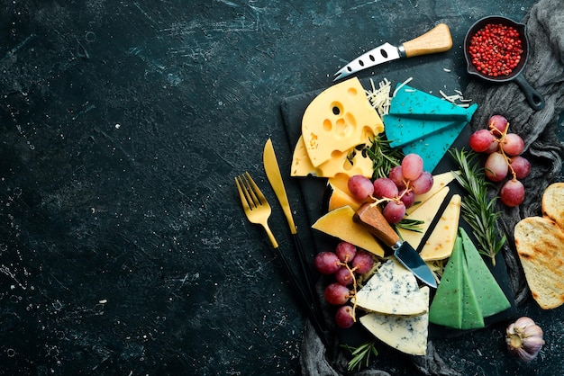 Grande conjunto de uvas de nozes de queijo e lanches em um fundo de pedra preta Espaço para cópia grátis Vista superior