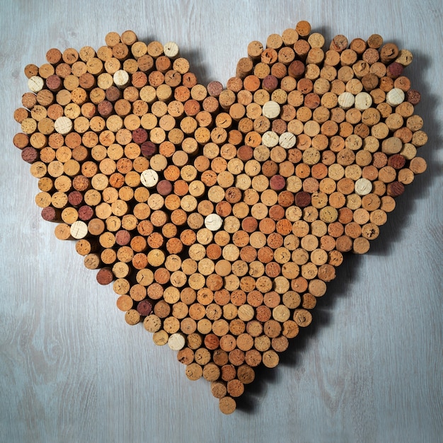 Grande coração feito de rolhas de cortiça em fundo de madeira, design de vinho concent