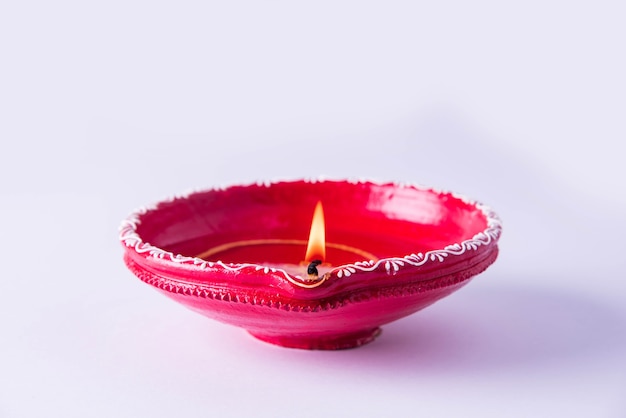 Foto grande diya decorativo de argila vermelha ou lâmpada de óleo acesa durante o festival de diwali. foco seletivo