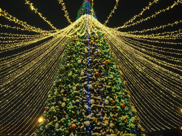 Grande e linda árvore de Natal com decorações e iluminações na noite de neve Ano novo e fundo de férias de Natal Paisagem festiva da cidade de inverno