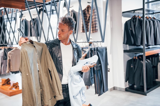 Grande escolha Jovem na loja moderna com roupas novas Roupas elegantes e caras para homens