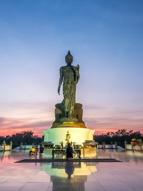 Grande estátua de Buda ambulante a estátua principal da diocese budista sob o céu crepuscular na Tailândia