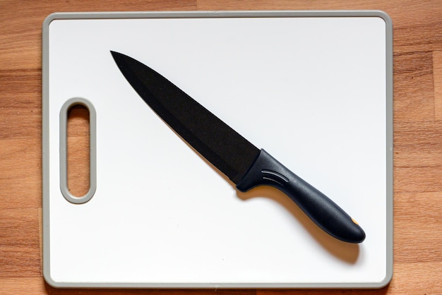 Grande faca preta em uma prancha em uma mesa de madeira de cozinha