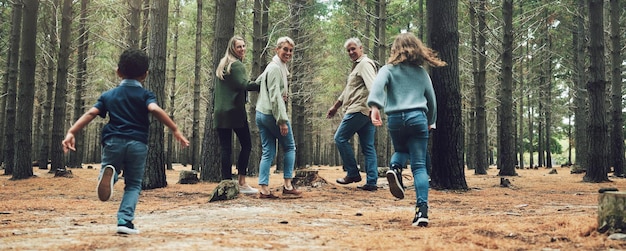 Grande família da floresta e aventura com crianças, pais e avós caminhando na natureza para diversão em caminhadas ao ar livre e árvores em férias de bem-estar Crianças correndo viajam e homens e mulheres felizes na madeira