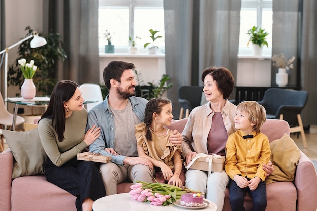 Grande família de cinco pessoas sentada no sofá em casa