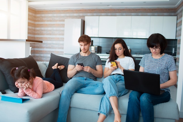 Grande família em casa. Todo mundo usa seu próprio gadget. Dependência de redes sociais e jogos para celular. Tablet, smartphone e laptop em vez de diversão conversando à noite