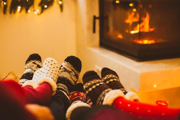 Grande família está se aquecendo perto da lareira no dia frio de inverno Foco interior moderno nas meias