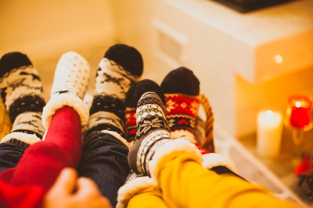 Grande família está se aquecendo perto da lareira no dia frio de inverno Foco interior moderno nas meias