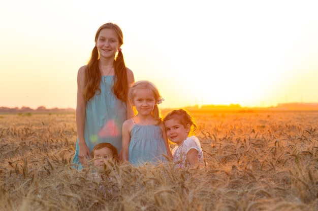 Grande família feliz. quatro meninas de diferentes idades no campo de trigo