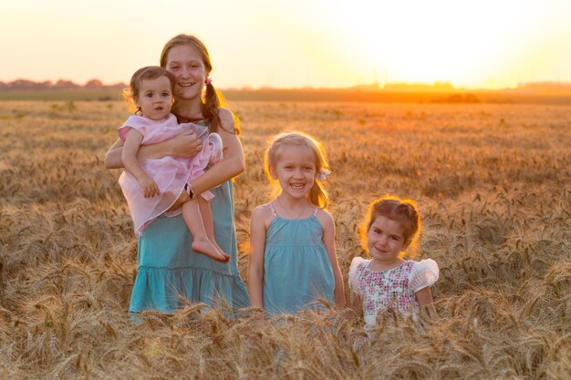 Grande família feliz. quatro meninas de diferentes idades no campo de trigo