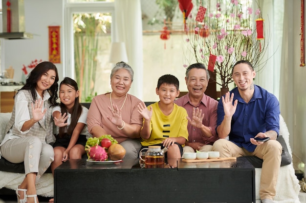 Grande família feliz tomando chá e frutas frescas em casa ao comemorar o tet