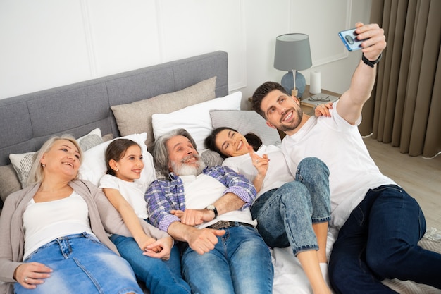 Grande família multigeracional, pai, mãe e avós sênior com uma menina tirando uma selfie