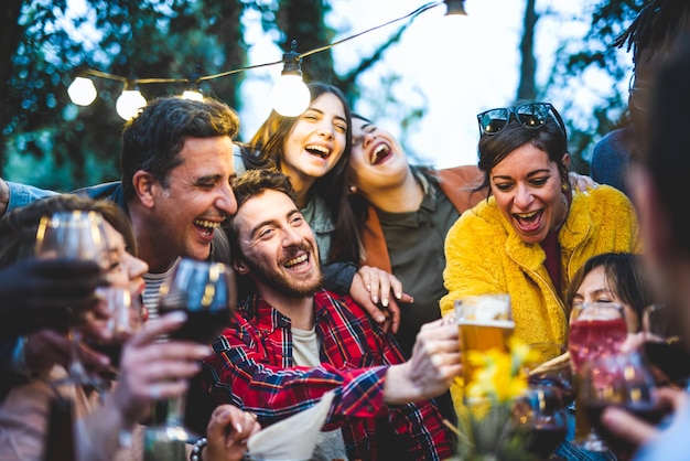 Grande grupo de amigos felizes se divertindo na festa de comemoração pessoas de faixa etária mista comemorando feriado comendo juntos pessoas se abraçando e brindando com bebidas foco seletivo nas pessoas