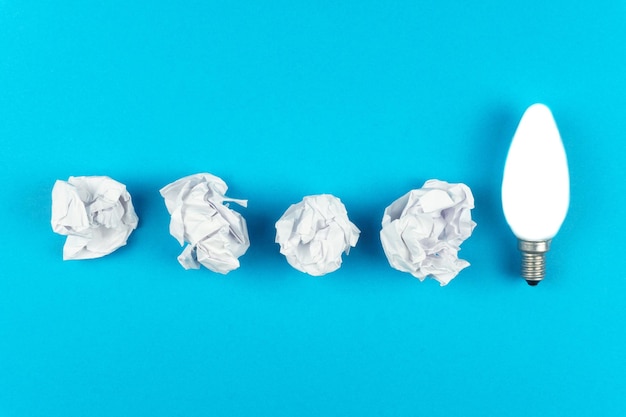 Grande ideia conceito com papel amassado e uma lâmpada em um fundo azul