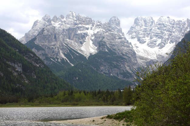 Grande lago de montanha com montanhas nevadas ao fundo, dolomitas itália