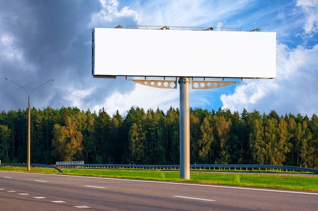 Grande maquete vazia billboard ao longo de uma rodovia com floresta em fundo de céu azul com lindas nuvens.