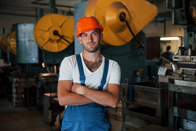 Grande máquina de produção atrás. Retrato do engenheiro em uma fábrica metalúrgica em capacete protetor.