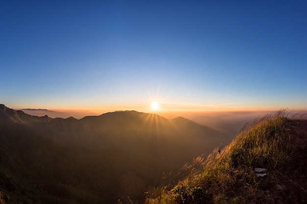 Grande nascer do sol acima do vale da montanha e da névoa da manhã.