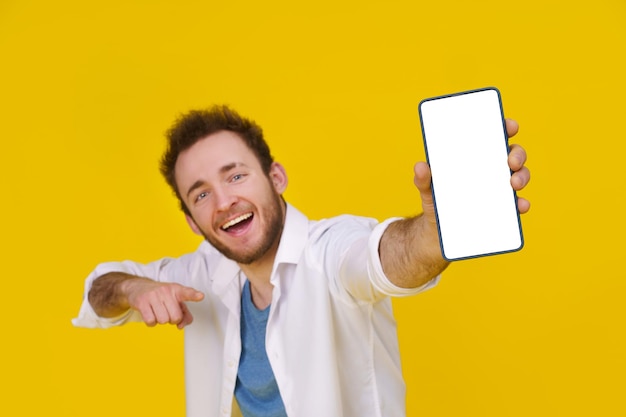 Grande oferta Jovem feliz segurando smartphone mostrando uma tela branca vazia e emocionante para ganhar isolado sobre fundo amarelo comemorando o sucesso Colocação de produtos Espaço vazio ou espaço de cópia