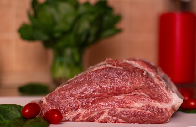 Foto grande pedaço de carne de porco cru vermelho, tomate cereja e hortaliças