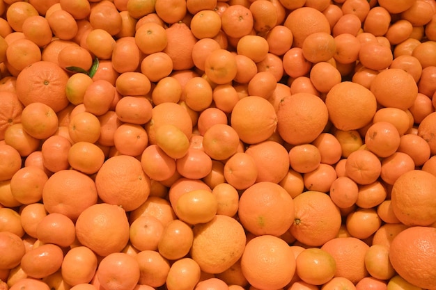 Grande pilha de laranjas maduras e tangerinas no balcão do mercado Fundo alimentar Conceito de colheita de frutas