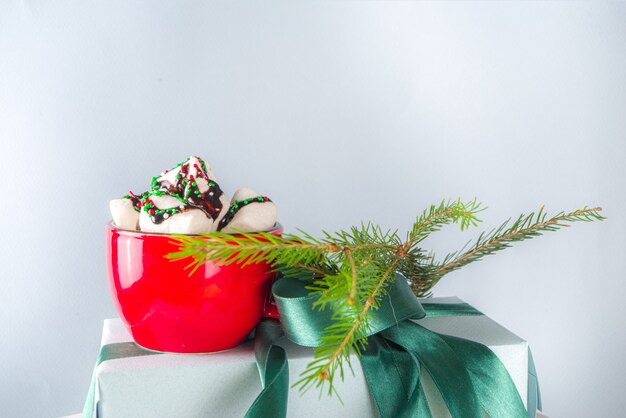 Grande pilha de presentes de Natal com chocolate quente, permaneça como um pedestal, caixas de presente de papel artesanal aconchegantes em tons pastéis com fita festiva de Natal verde, xícara de chocolate com marshmallow, espaço de cópia