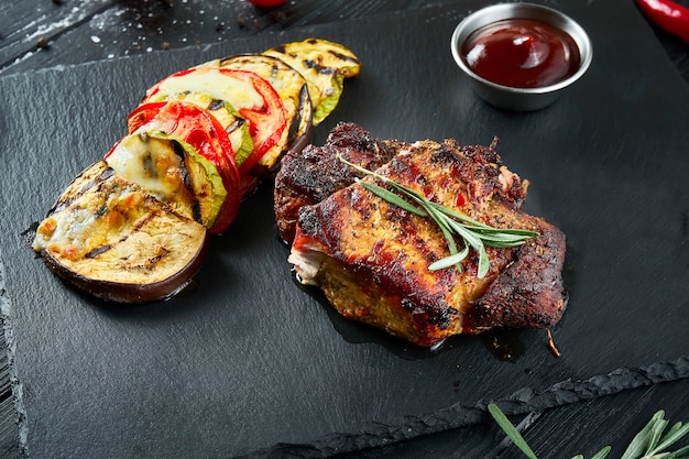 Grande porção de bife de porco delicioso com legumes grelhados em uma placa de cerâmica em uma superfície de madeira.