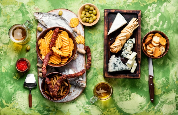 Grande seleção de lanches para cerveja. Conjunto de queijos, peixe, batatas fritas e snacks. Cerveja e petiscos