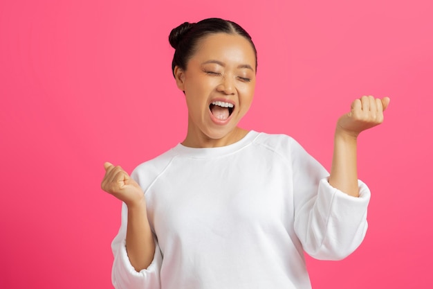 Grande sorte feliz excitada mulher asiática comemorando o sucesso em fundo rosa