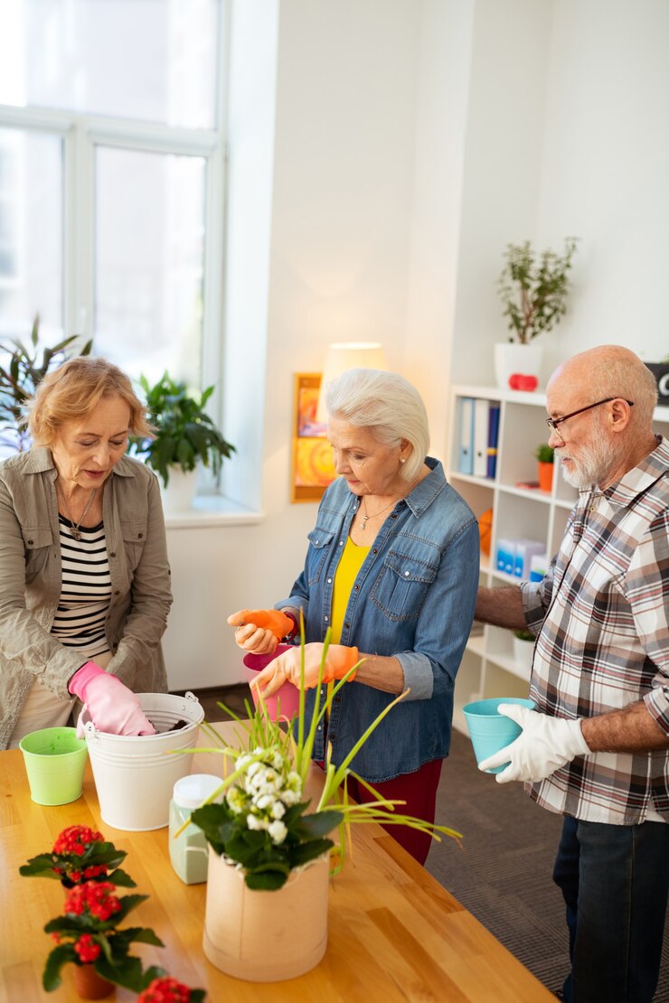 Foto grande time. agradáveis idosos plantando flores enquanto trabalham juntos como uma equipe