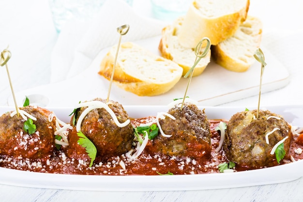 Grandes albóndigas italianas adornadas con cilantro y queso parmesano como aperitivo.