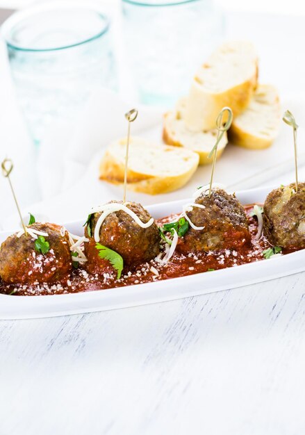 Grandes almôndegas italianas guarnecidas com coentro e queijo parmesão como aperitivos.