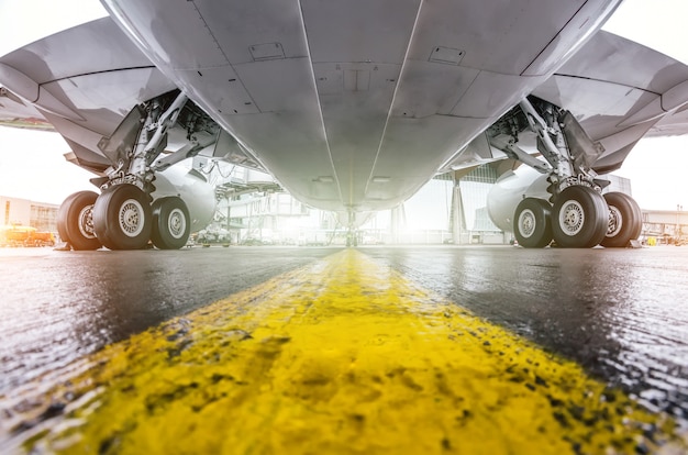 Grandes aviões de passageiros estacionados no aeroporto, asa de vista inferior e trem de pouso.