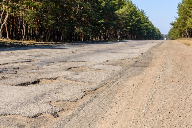 Grandes baches en la carretera de asfalto dañada