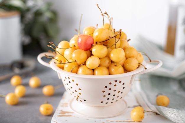 Grandes cerezas amarillas maduras en un colador pequeño