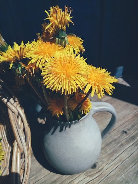 grandes flores amarelas em vaso na mesa rústica azul