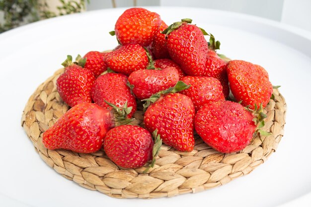 Foto grandes fresas rojas maduras sobre un lecho de paja sobre un fondo blanco.