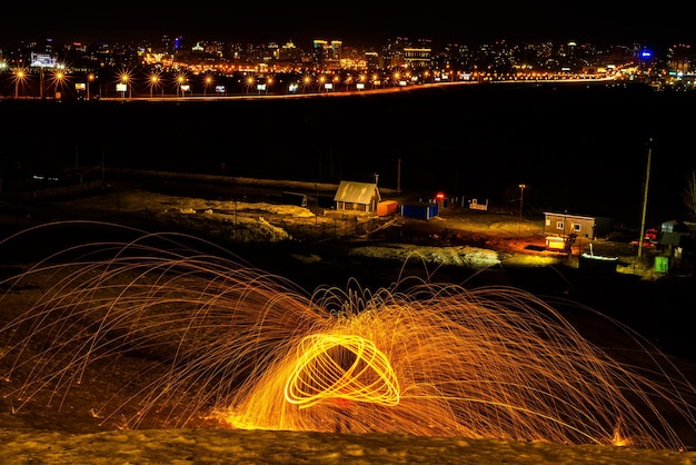 Grandes fuegos artificiales redondos brillan desde la lana de acero en llamas que la ciudad ilumina por la noche