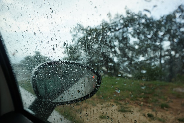 Grandes gotas de chuva escorrem pelo pára-brisa do carro, a vista do carro.