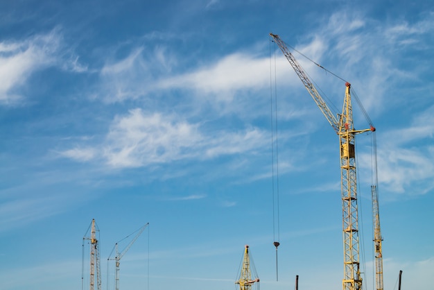 Grandes grúas torre contra el cielo azul. Imagen del primer del material de construcción con el espacio de la copia. Construir de ciudad.