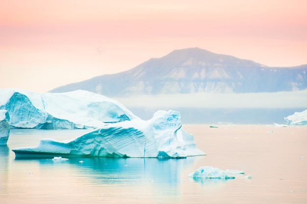 Grandes icebergs azuis na vila de Saqqaq ao pôr do sol, oeste da Groenlândia