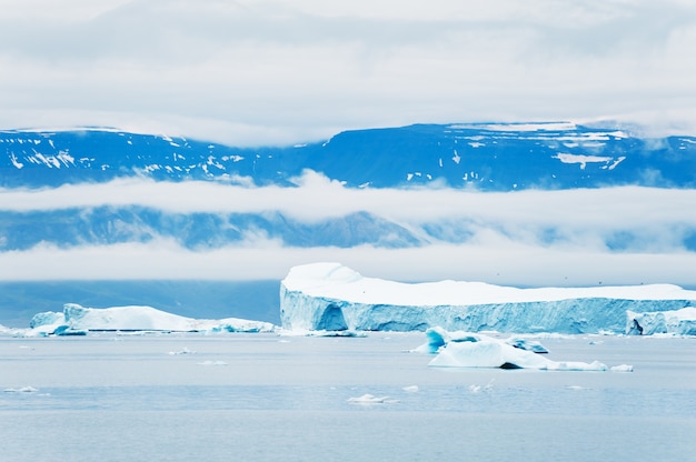 Grandes icebergs no Oceano Atlântico e mointsins com nuvens. Aldeia de Saqqaq, oeste da Groenlândia.