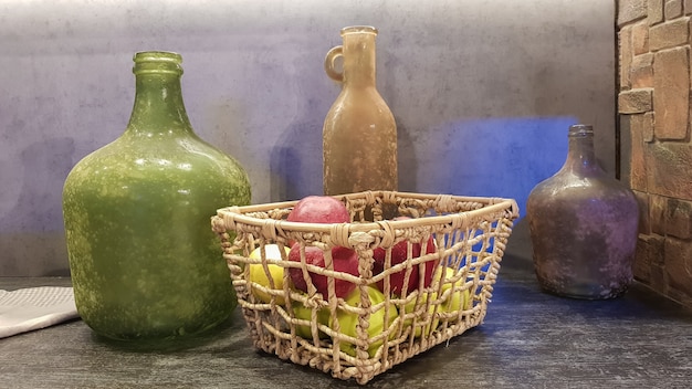 Grandes jarrones de vidrio, una canasta con manzanas y platos en el interior de una cocina moderna. La combinación de madera y hormigón en el diseño. Cocina comedor de estilo moderno.