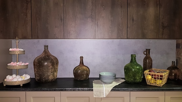 Grandes jarrones de vidrio, una canasta con manzanas y platos en el interior de una cocina moderna. La combinación de madera y hormigón en el diseño. Cocina comedor de estilo moderno.