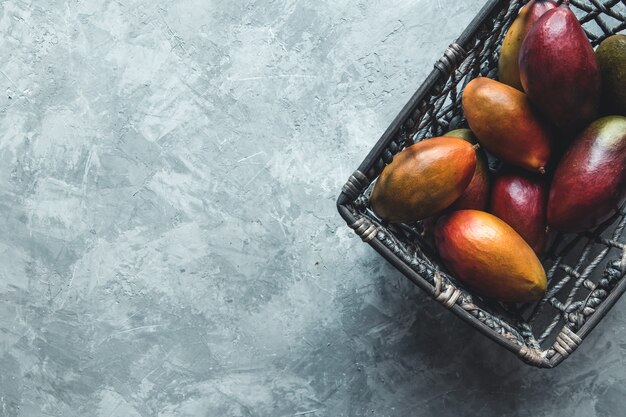 grandes mangos en una canasta de mimbre sobre un fondo gris. Comida sana, vegana