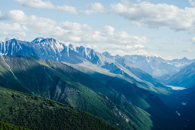 Grandes montañas, glaciares y bosques verdes con un lago alpino y un río.