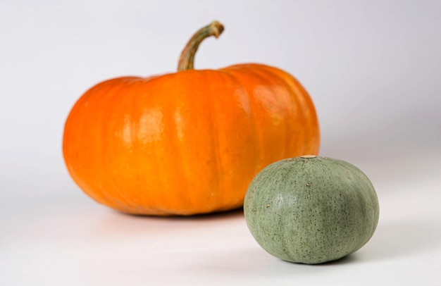 Grandes naranjas y pequeñas calabazas verdes sobre fondo blanco Otoño