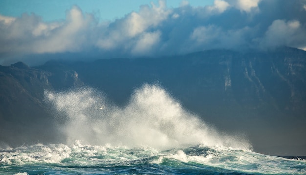 Foto grandes ondas quebram nas rochas do mar, no contexto da costa.