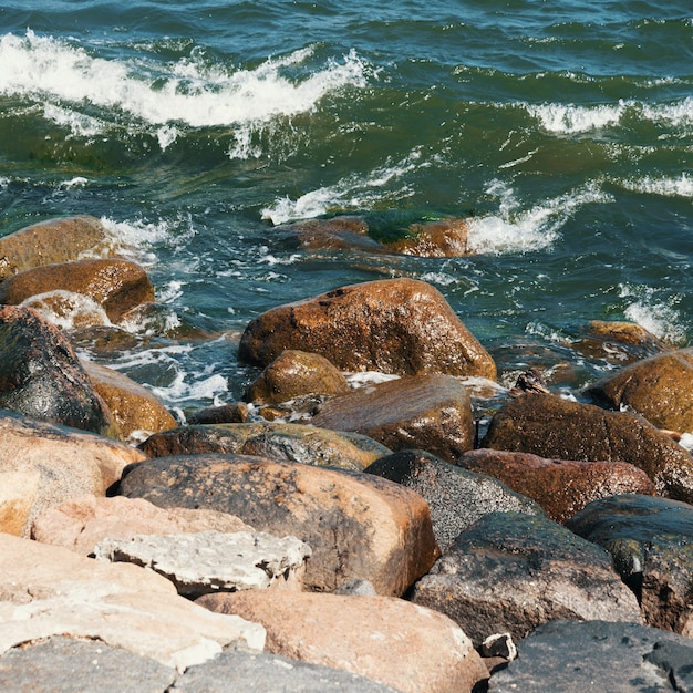 Grandes pedras caem na praia em frente às ondas